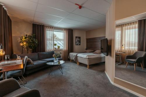 een woonkamer met een bank en een bed bij Hotell Entré Norr in Umeå