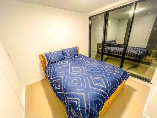um quarto com uma cama com edredão azul e uma janela em 2BR Mason Square @ Moonee Ponds em Melbourne