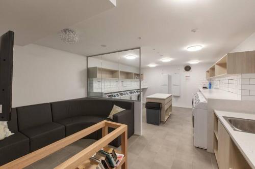 a living room with a black couch in a kitchen at 2BR Mason Square @ Moonee Ponds in Melbourne