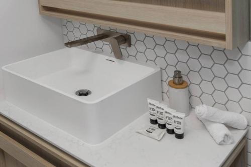 a white sink and some toiletries on a counter at 2BR Mason Square @ Moonee Ponds in Melbourne