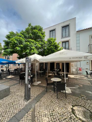 an outdoor patio with tables and chairs and umbrellas at Pérola Branca in Lagos