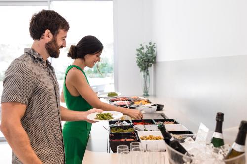 a man and woman standing in a kitchen preparing food at Petit Sagitario Adults only in Ciutadella