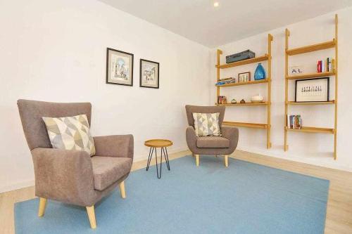 a living room with two chairs and a table and shelves at Prestige Sunset Carcavelos Beach - Checkinhome in Carcavelos