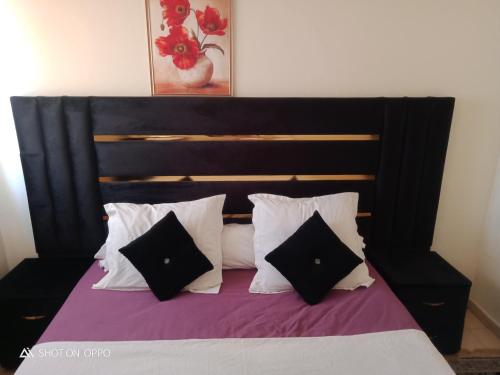 a bedroom with a black and white bed with pillows at Les jardaine d'ifrane in Ifrane