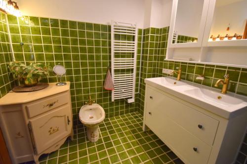 a green tiled bathroom with a sink and a toilet at Chambre d'hôtes et Spa en Luberon in Volx