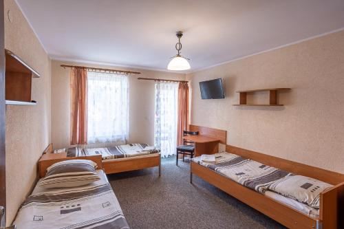 a room with two beds and a table and a desk at Centrum Halniak in Istebna