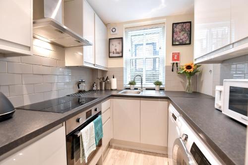 uma cozinha com armários brancos, um lavatório e um micro-ondas em Kingsley Apartments Tower Bridge em Londres