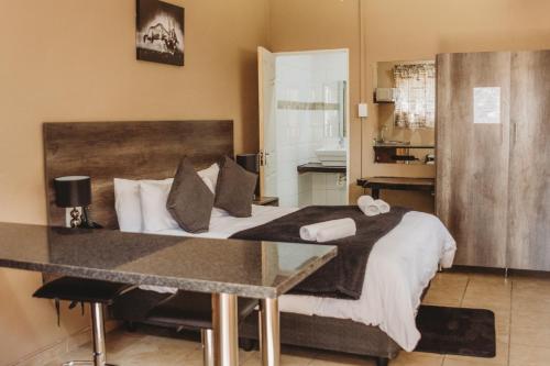 a bedroom with a large bed with a table at Casa Leitao Lodge in Phalaborwa