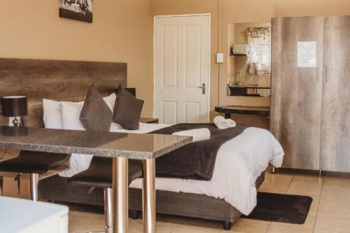 a bedroom with a bed with a desk and a table at Casa Leitao Lodge in Phalaborwa
