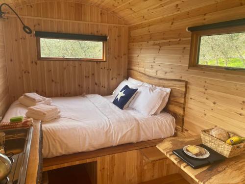 Orchard retreat off grid shepherds huts in Dorset في دورتشستر: غرفة نوم مع سرير في كابينة خشب