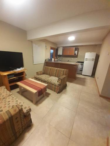 sala de estar con 2 sofás y cocina en Departamentos Tres de Caballería en San Martín de los Andes
