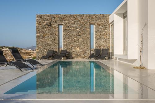 a swimming pool with chairs and a building at THEIA VILLA in Adamas