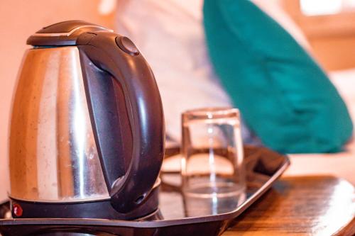 a tea kettle and a glass on a table at Triple One Hostel Tapovan Rishikesh in Rishīkesh