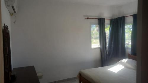 a bedroom with a bed and a window with blue curtains at CASA DE CAMPO in Helvecia