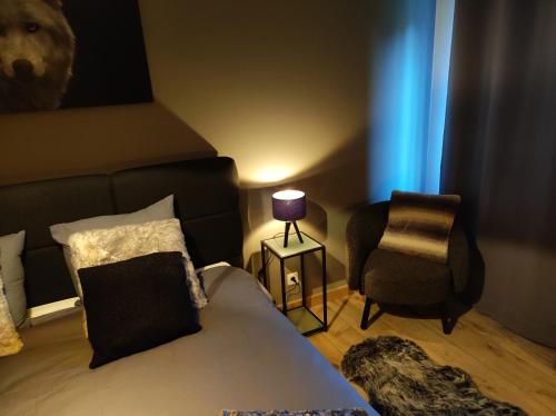a bedroom with a bed and a chair and a lamp at Gîte La Renéade in Foyr