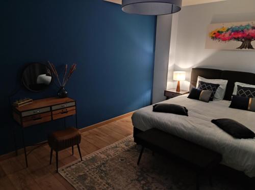 a bedroom with a large bed and a blue wall at Gîte La Renéade in Foyr