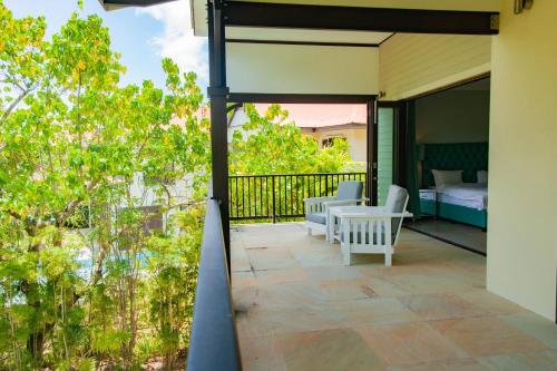 a balcony of a house with a bed and chairs at Maison La Plage by Simply-Seychelles in Eden Island