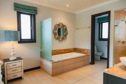 a bathroom with a tub and a toilet and a sink at Maison La Plage by Simply-Seychelles in Eden Island