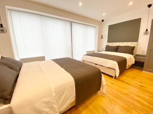 two beds in a hotel room with wood floors at Goodwin St in London