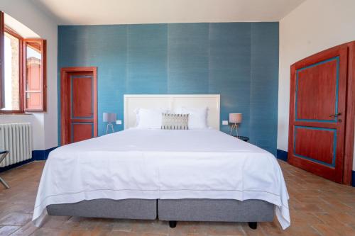 a bedroom with a large white bed with blue walls at Agriturismo Il Sarale - Umbria in Città di Castello
