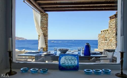 a table with blue cups and a view of the ocean at Fantastic waterfront home in Koundouros, Kea in Ioulida