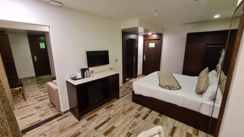 Habitación de hotel con cama y TV en Regenta Inn Ranip Ahmedabad, en Ahmedabad