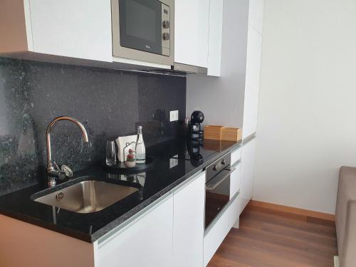 une cuisine avec un évier et un micro-ondes dans l'établissement PIMENTA FOUR HOUSE, à Amarante