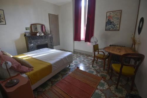 sypialnia z łóżkiem, stołem i kominkiem w obiekcie Maison Mômes w mieście Bize-Minervois