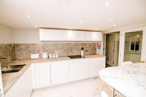 a white kitchen with white cabinets and a table at Spacious 2 bed city centre apartment with parking in Norwich