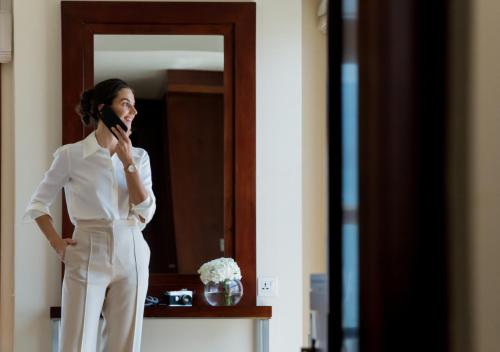 a woman in a white suit talking on a cell phone at Dusit Thani Dubai in Dubai