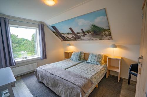 デ・コーフにあるDe Ruige Hoogteのベッドルーム1室(ベッド1台付)が備わります。壁には絵画が飾られています。