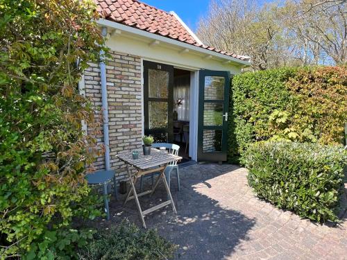 a table and chairs in front of a house at Bed & Bos de 14 Sterren in Den Burg
