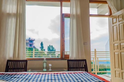 a dining room with a table and a large window at Jot Eco Boutique Stays in Dharamshala