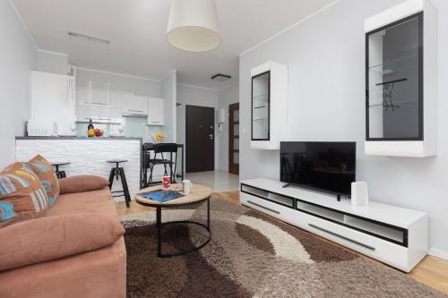 a living room with a couch and a tv at Warsaw Young City Apartment by Renters in Warszawa