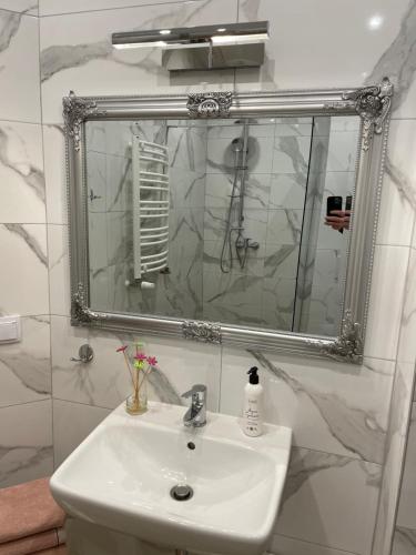 La salle de bains est pourvue d'un lavabo et d'un miroir. dans l'établissement Komfort Apartament, à Nałęczów