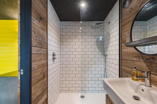 y baño con lavabo y ducha con azulejos blancos. en Lark Rise by Bloom Stays en Camber