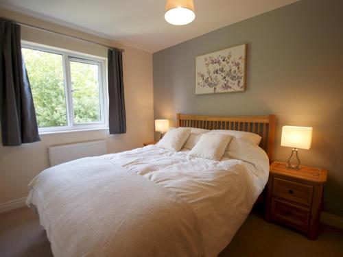 1 dormitorio con 1 cama con 2 lámparas y una ventana en Pass the Keys Homely and central with parking, en Exeter