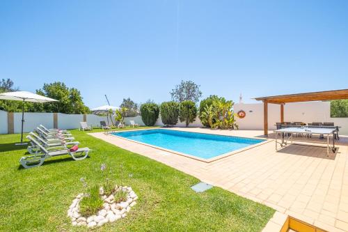 un patio trasero con piscina, mesa y sillas en Villa Valentina by Algarve Vacation, en Almancil