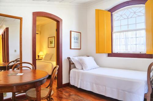 a small room with a bed and a table and a window at Pousada do Ouro in Paraty