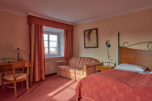 una camera d'albergo con letto, sedia e scrivania di Hotel Donauhof a Deggendorf
