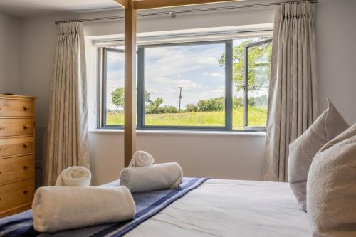 a bedroom with a bed with a large window at The Grove - Converted Cattle Barn in Malmesbury