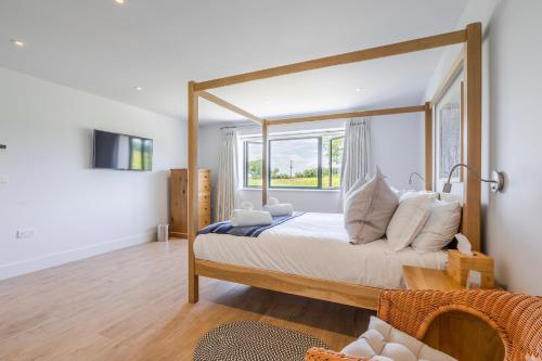 1 dormitorio con cama con dosel y ventana en The Grove - Converted Cattle Barn, en Malmesbury