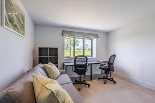 a living room with a couch and a table and chairs at The Grove - Converted Cattle Barn in Malmesbury