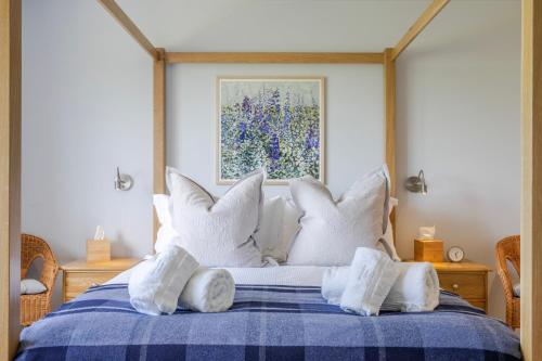 a bedroom with a blue and white bed with white pillows at The Grove - Converted Cattle Barn in Malmesbury