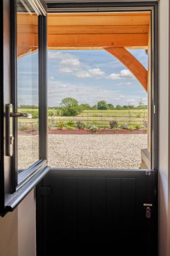 an open door with a view of a field outside at The Grove - Converted Cattle Barn in Malmesbury