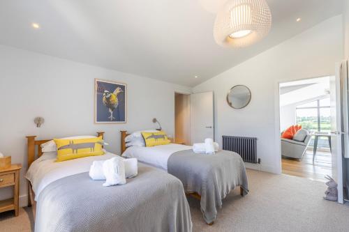 two beds in a room with white and yellow pillows at The Grove - Converted Cattle Barn in Malmesbury