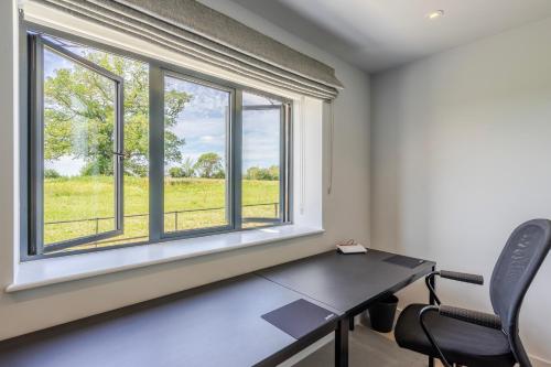a room with a table and two windows at The Grove - Converted Cattle Barn in Malmesbury