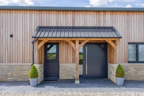 a garage with a black roof on a building at The Grove - Converted Cattle Barn in Malmesbury