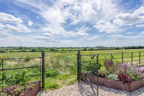 a gate leading to a field with flowers at The Grove - Converted Cattle Barn in Malmesbury