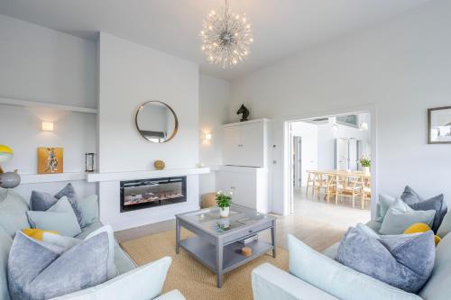 a living room with white furniture and a fireplace at The Grove - Converted Cattle Barn in Malmesbury